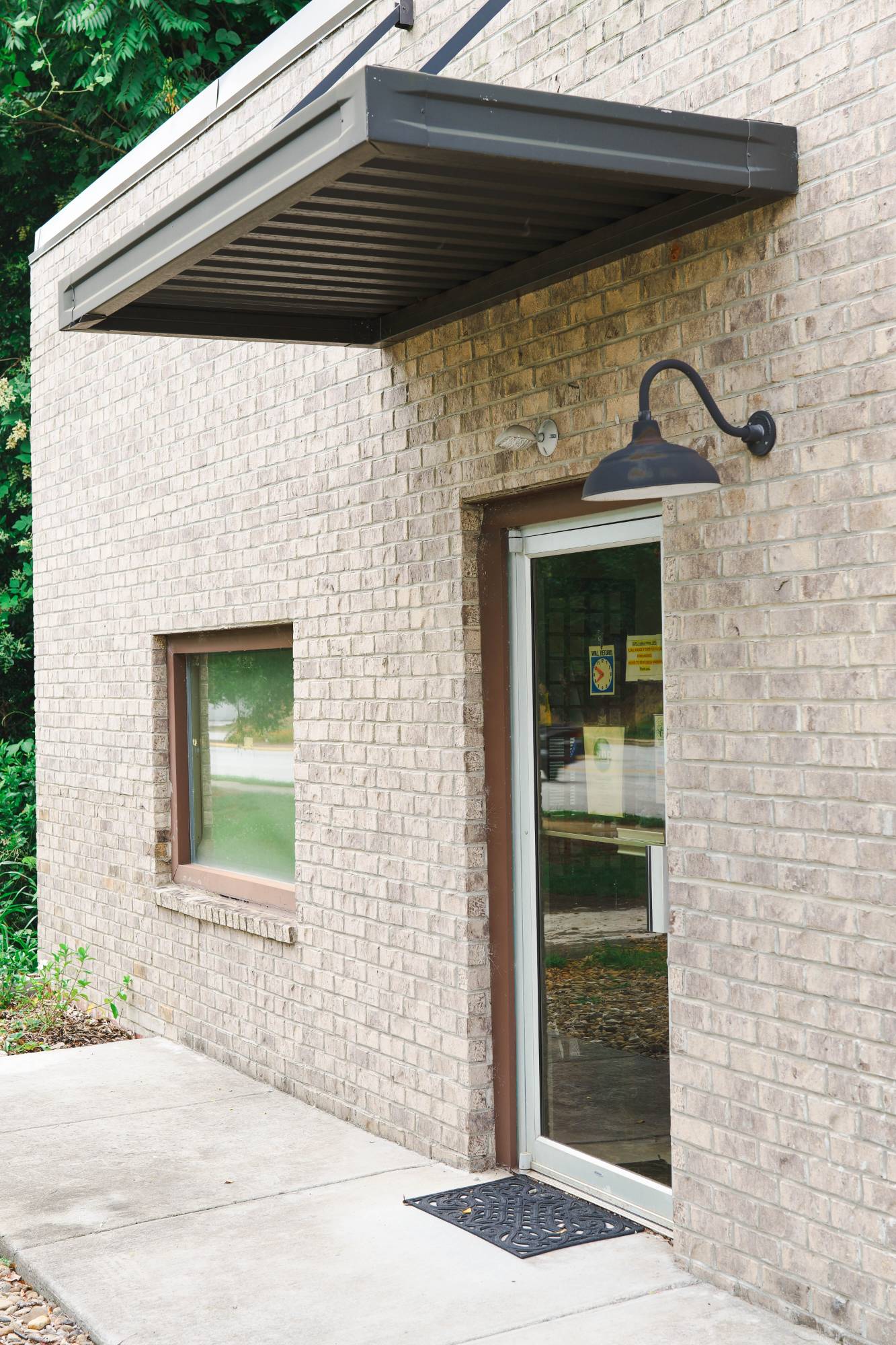 Front entrance of Integrative Health Partners clinic in Greenville, SC — glass door with gooseneck lamp and covered entryway