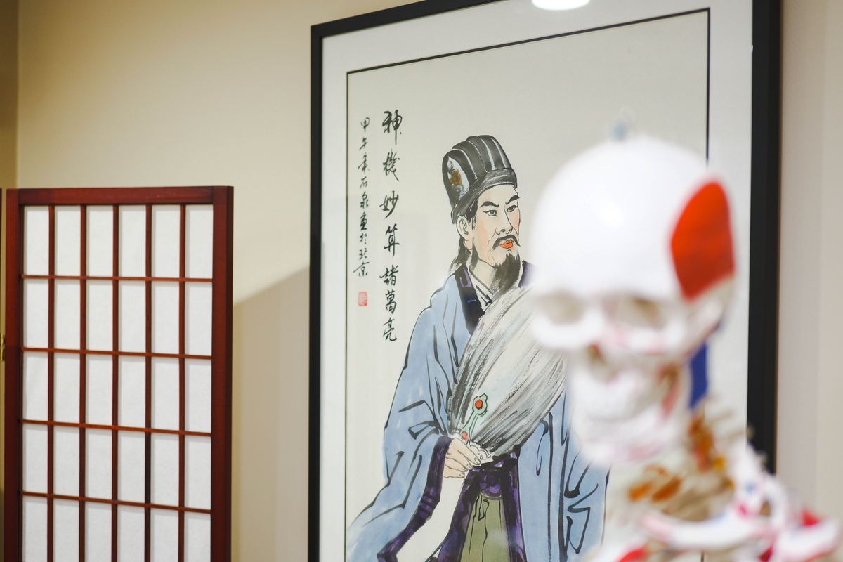 Classical Chinese physician painting in treatment room at Integrative Health Partners Greenville — traditional Chinese medicine art with anatomical skull model in foreground